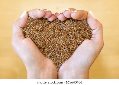 Flax seeds in woman's hands shaping heart