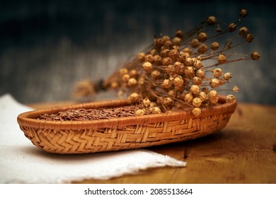 Flax Seeds In Wooden Basket And Dry Flax Plant Stems, Selective Focus, Close Up.