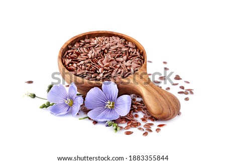 Flax seeds in wooden spoon with flowers on white background.