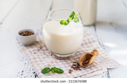 Flaxseed Milk In Glass And Bottle, Napkin, Flax Seeds, Mint Leaves.