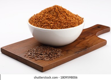 Flaxseeds ,Brown flaxseeds powder or  chutney in a ceramic bowl with whole flaxseeds on wooden plank