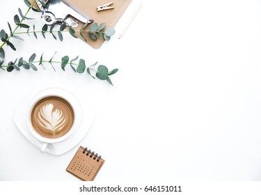 Flay lay, Top view office table desk. Feminine desk workspace frame with green leaves eucalyptus, clipboard and coffee  on white background.  ideas, notes or plan writing concept
