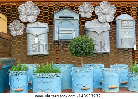 Flea market window shop with gardening decoration - vintage metal flowerpots with herbs and rusty postboxes               
