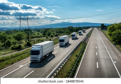 Fleet or Convoy of big transportation trucks in line  on a countryside highway under a blue sky