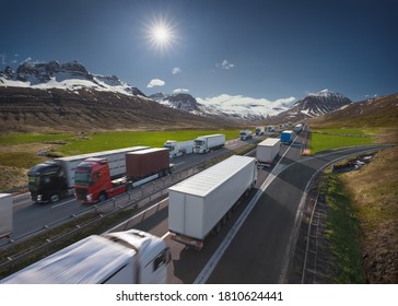 Fleet Of Delivery Semi Trucks With Container On Highway Driving Through The Mountain Range Towards The Sun. Transportation Industry Concept.