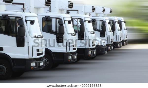 A fleet of delivery\
truck vehicles used to transport refrigerated goods, high dynamic,\
motion blurred. 