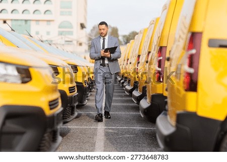 Fleet manager inspecting rows of yellow delivery vans