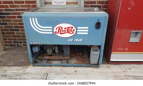 FLEETWOOD, PENNSYLVANIA,US - April 3, 2021: Antique Chest Pepsi Machine Collects Leaves On A Porch. 