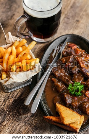 flemish stew with french fries, gingerbread and brown beer on wooden table