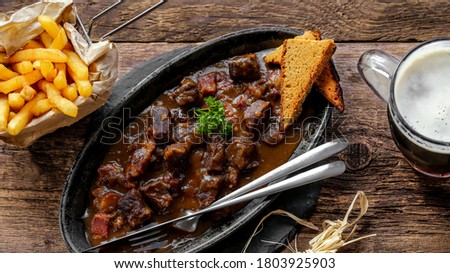 flemish stew with french fries, gingerbread and brown beer on wooden table
