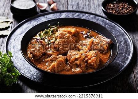 Flemish Stew, stoofvlees, carbonnade, beef or pork, beer and onion stew in black bowl on dark rustic wooden table