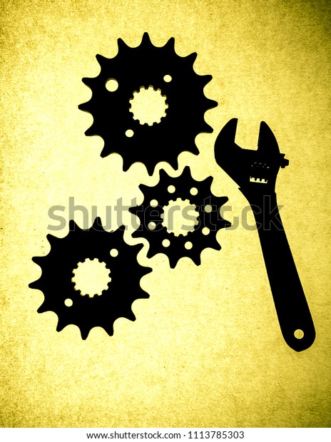flex-head wrench and gearbox sprockets at\
yellow illuminated\
background