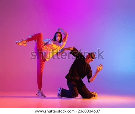 Flexibility and grace. Two young people, guy and girl, dancing contemporary dance over pink background in neon light. Modern dance aesthetics concept