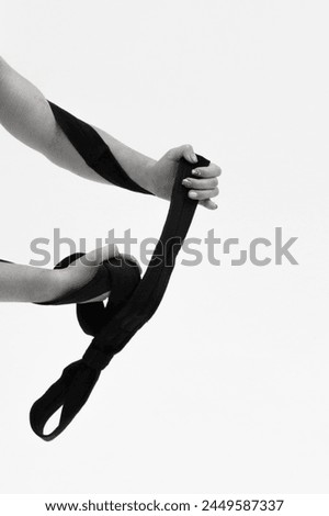 A Flexible aerial gymnast performs on gymnastic slings. Aerial circus show. Stretching of the young woman. In the air. Athletic girl. Monochrome. Athletic hands. 