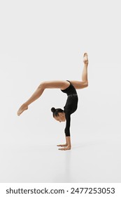 Flexible and artistic young girl, rhythmic gymnast showing skills and talent, training, performing isolated on white background. Concept of sport, retro and vintage, active lifestyle, hobby