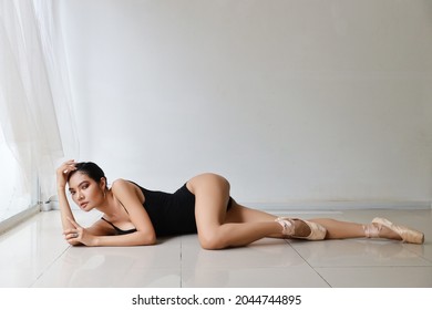 Flexible Asian Ballet Dancer Stretching On White Wall Studio