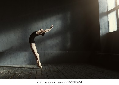 Flexible ballet dancer stretching in the dark lighted studio - Shutterstock ID 535138264