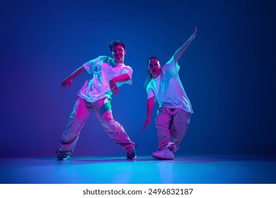 Flexible and energetic young people, man and woman dancing hip-hop, performing with passion against purple studio background in neon light. Concept of contemporary dance, hobby, youth - Powered by Shutterstock