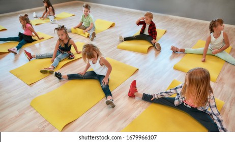 Flexible kids. Group of children sitting on the floor and doing gymnastic exercises in the dance studio. Physical education. Sport concept. Healthy lifestyle. Active hobbies - Powered by Shutterstock