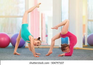 Flexible kids gymnasts doing acrobatic exercise in gym. Sport, training, fitness, yoga, active lifestyle concept