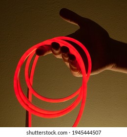 Flexible Red Led Tape Neon In Hand On Black Background.