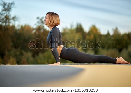 flexible woman bends, stretching body during yoga outdoors, on fresh air, alone. woman lead healthy lifestyle , engaged in sport