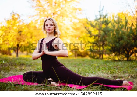 Flexible woman doing yoga in the autumn park