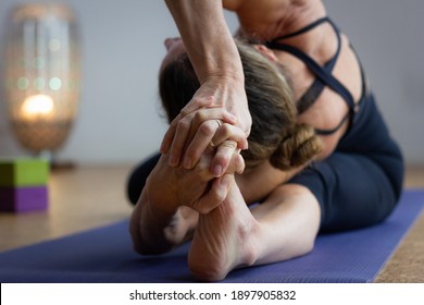 Flexible Yogi Leaning Head Towards Left Leg And Hands Holding Foot In Studio. Woman In Black Outfit Practices Ashtanga Yoga Parighasana Pose Of Intermediate Series. Advanced Practitioner Concept