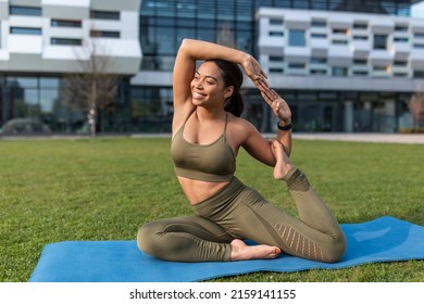 Flexible Young Black Woman Doing Yoga Pigeon Pose During Outdoor Practice At City Park, Copy Space. Millennial African American Lady Stretching On Mat, Enjoying Pilates Outside In Summer