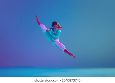 Flexible young girl, passionate hip hop dancer in motion on stage, performing dynamic moves against gradient blue background in neon light. Concept of freestyle dance, modernity, urban culture, youth