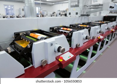 Flexographic printing machine with an ink tray, ceramic anilox roll, doctor blade and a print cylinder with polymer relief plate stuck on it. In-line press machine. Rotary or Flexo printing machine.