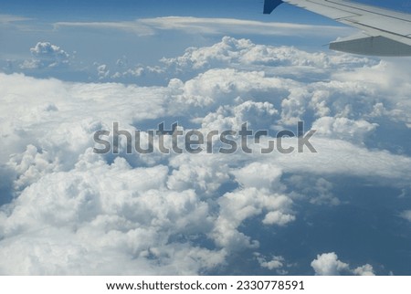 flies on an airplane high in the blue sky above white clouds. land landscape from above