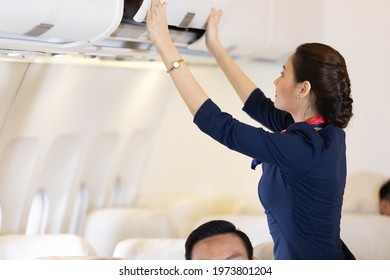 flight attendant checking and closing cabin compartment in airplane