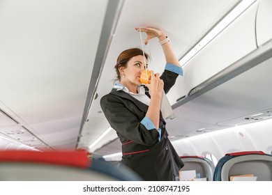 Flight Attendant Demonstrating How To Use Oxygen Mask In Airplane