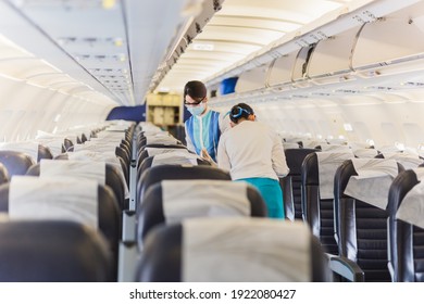 Flight Attendant In Face Mask Checking The Passenger Seat