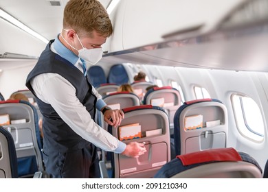 Flight Attendant In Face Mask Preparing Passenger Seat In Airplane