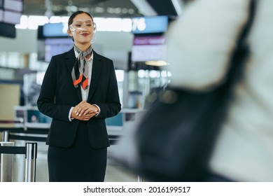 Flight Attendant With Face Shield Standing At Airport. Airport Staff During Pandemic Welcoming Travelers.