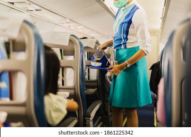 Flight Attendant In Facial Mask Serves Passengers A Coffee During Covid-19