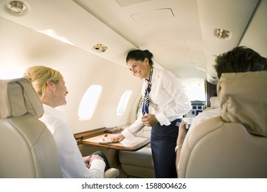 Flight attendant offering dessert to businesswoman on airplane - Powered by Shutterstock