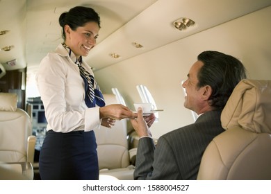 Flight attendant serving drink to businessman on airplane - Powered by Shutterstock