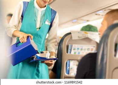 Flight Attendant Serving Drinks To Passengers On Board