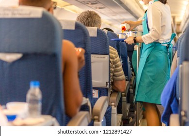 Flight Attendant Serving Drinks To Passengers On Board