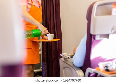 Flight Attendant Serving Drinks To Passengers On Board