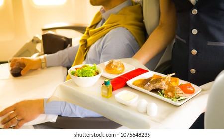 Flight Attendant Serving A Passenger In An Airplane