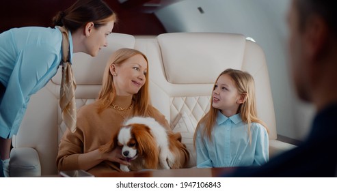 Flight Attendant Taking Order From Family In First Class Airplane Interior. Mother, Father, Daughter And Dog Travelling On Private Jet And Ordering Breakfast