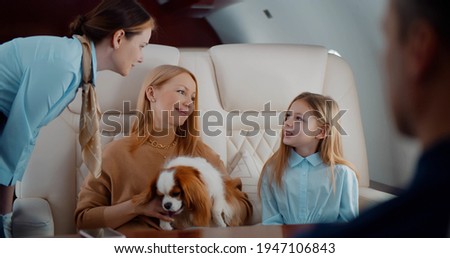 Flight attendant taking order from family in first class airplane interior. Mother, father, daughter and dog travelling on private jet and ordering breakfast