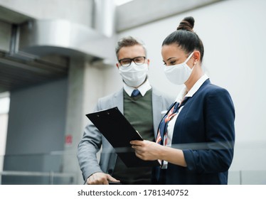 Flight attendant talking to mature businessman on airport, wearing face masks. - Powered by Shutterstock