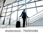 Flight attendant in uniform standing at the airport with a suitcase