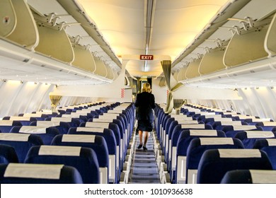 Flight Attendant Walking Down The Aisle In An Airplane