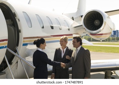 Flight attendant welcoming businesspeople to airplane - Powered by Shutterstock